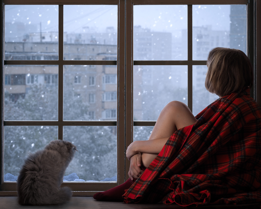 sad girl and cat looking out the window