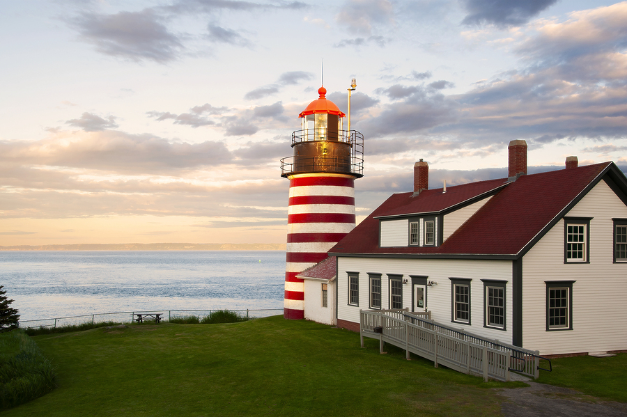 Sunset by West Quoddy Head lighthouse, with its red and white stripes, referred to as the "candy cane" lighthouse, in down east Maine, in New England. The beacon is located in the easternmost point in America.