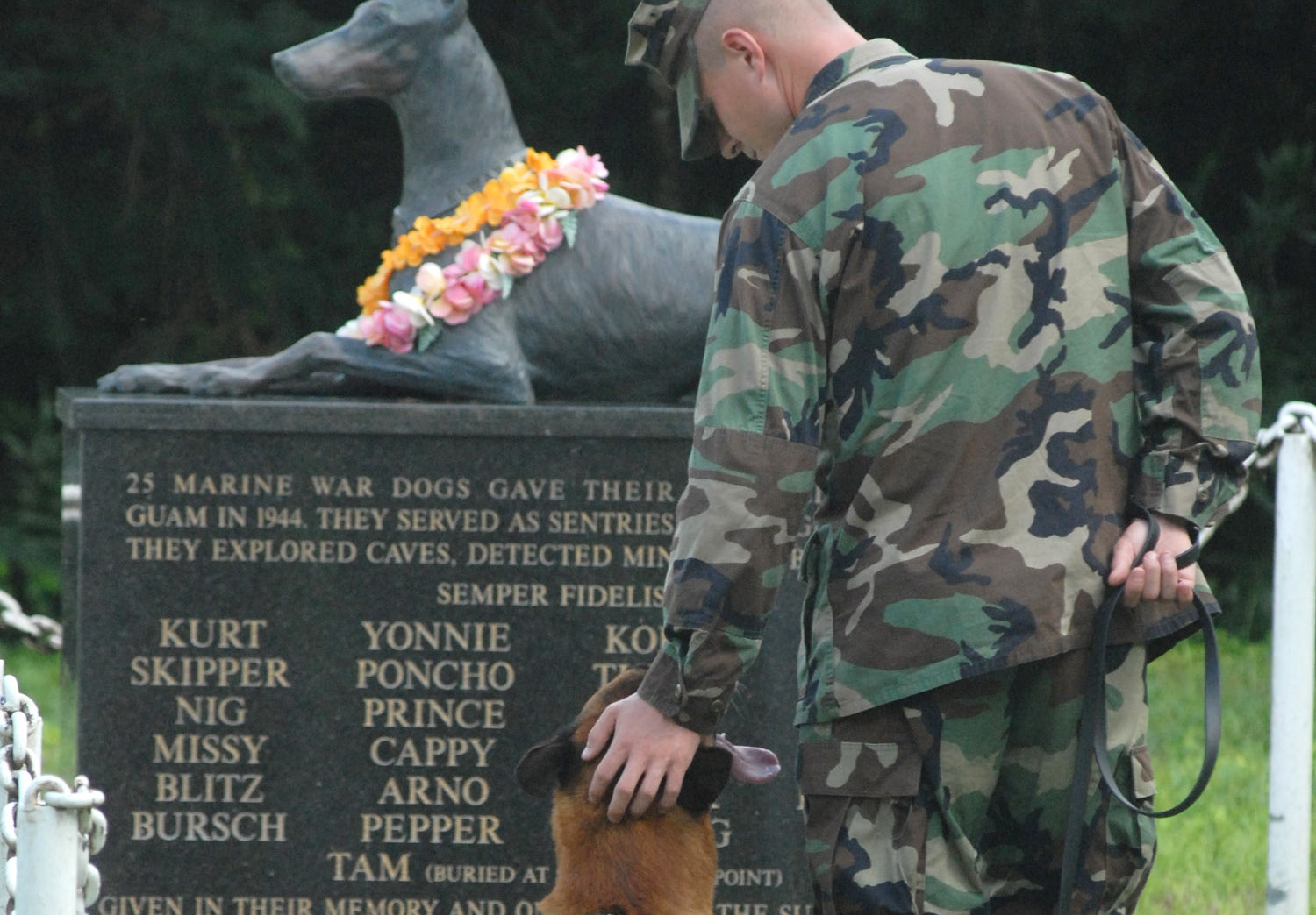 Santa Rita, Guam (October 27, 2006) ñ Petty Officer 2nd Class Blake Soller, a Military Working Dog (MWD) handler pets the head of MWD Rico, at the War Dog Cemetery located on Naval Base Guam Oct. 27. Soller is currently assigned to Naval Security Force Detachment Guam to the MWD kennel. U.S. Navy photo by Petty Officer 2nd Class John F. Looney